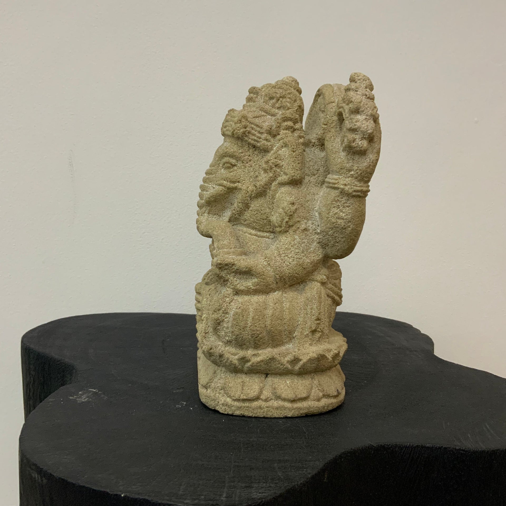 Ganesha Stone sculpture side figure on a black stand against a plain background