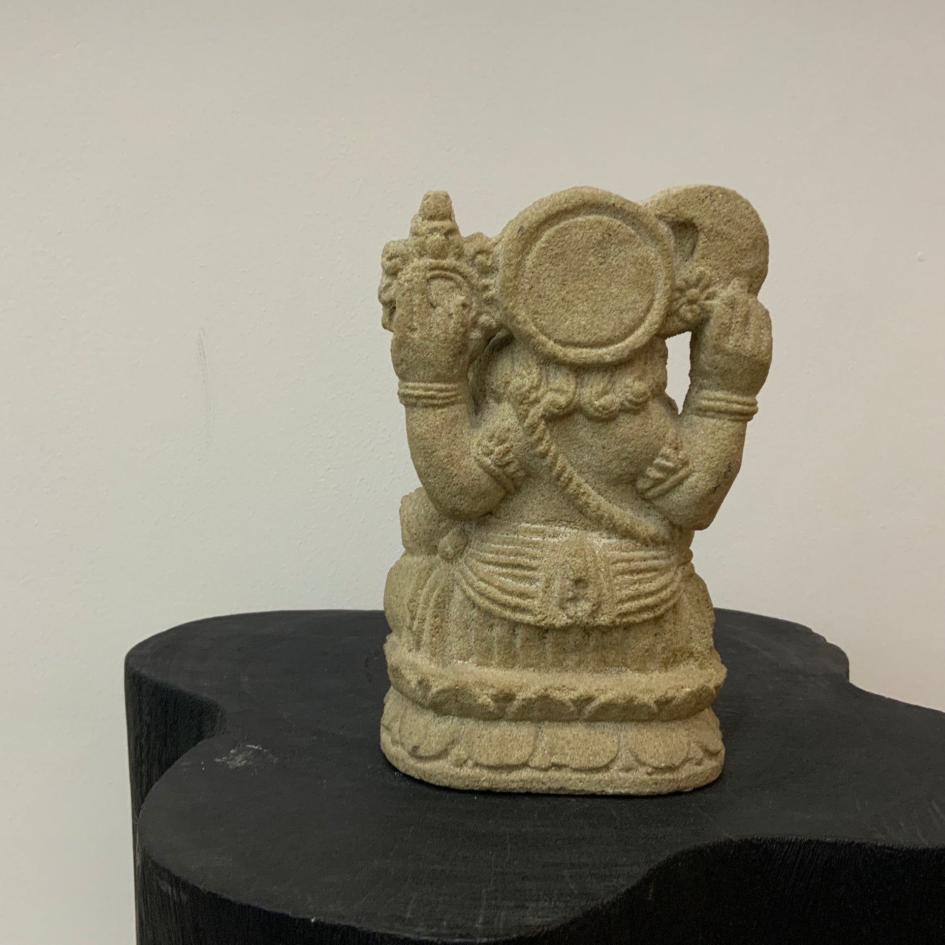 Ganesha Stone sculpture of a back figure on a black stand against a white background