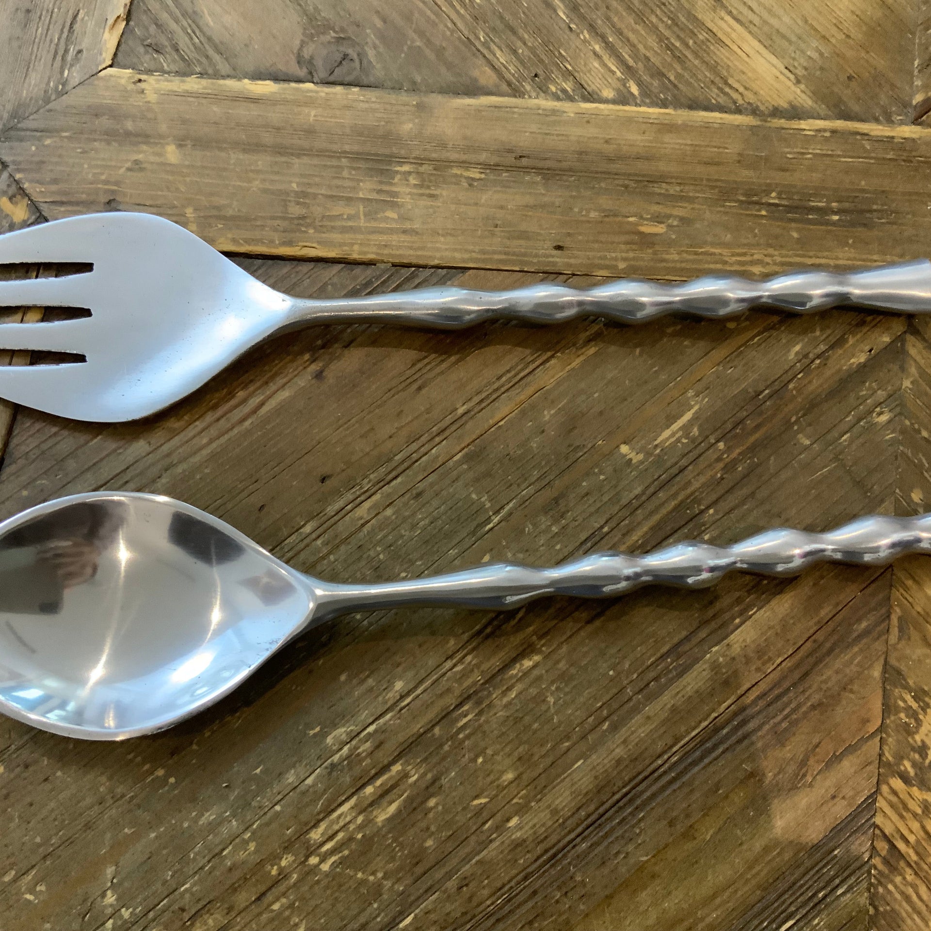 Modern silver salad serving set, in a wooden table.
