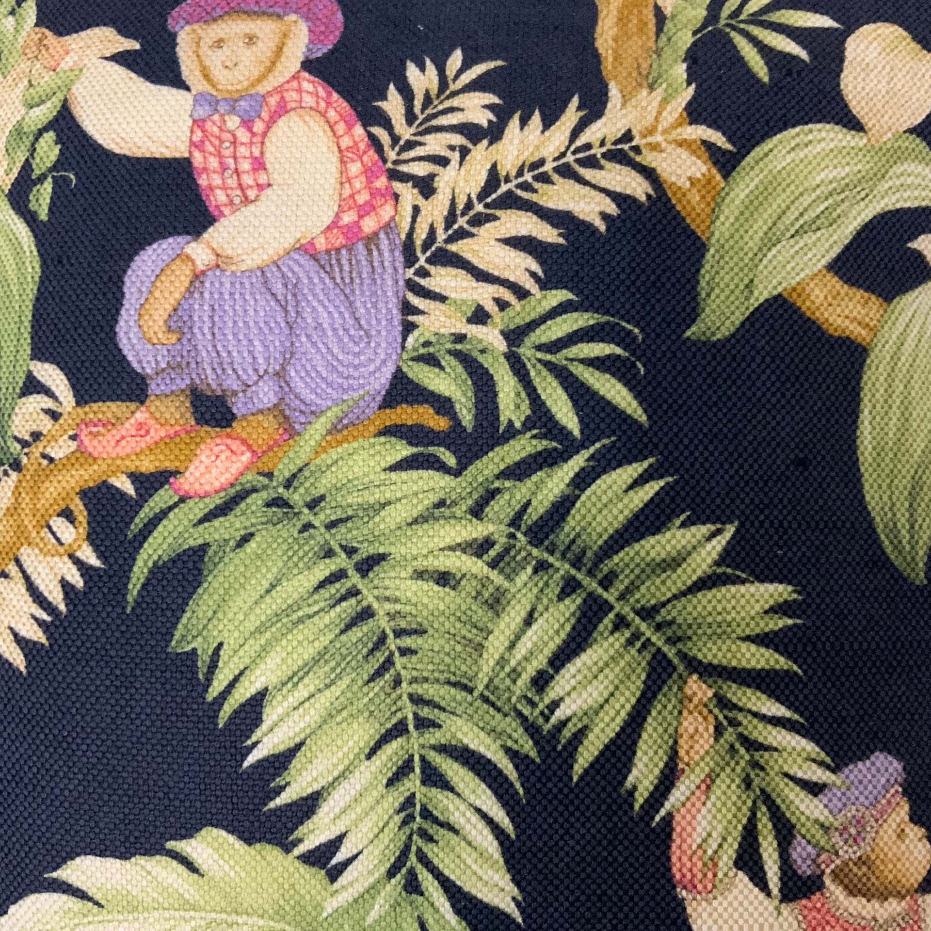 Decorative black throw cushion featuring a tropical jungle print with illustrated monkeys sitting on tree branches surrounded by lush green fern leaves and botanical foliage.
