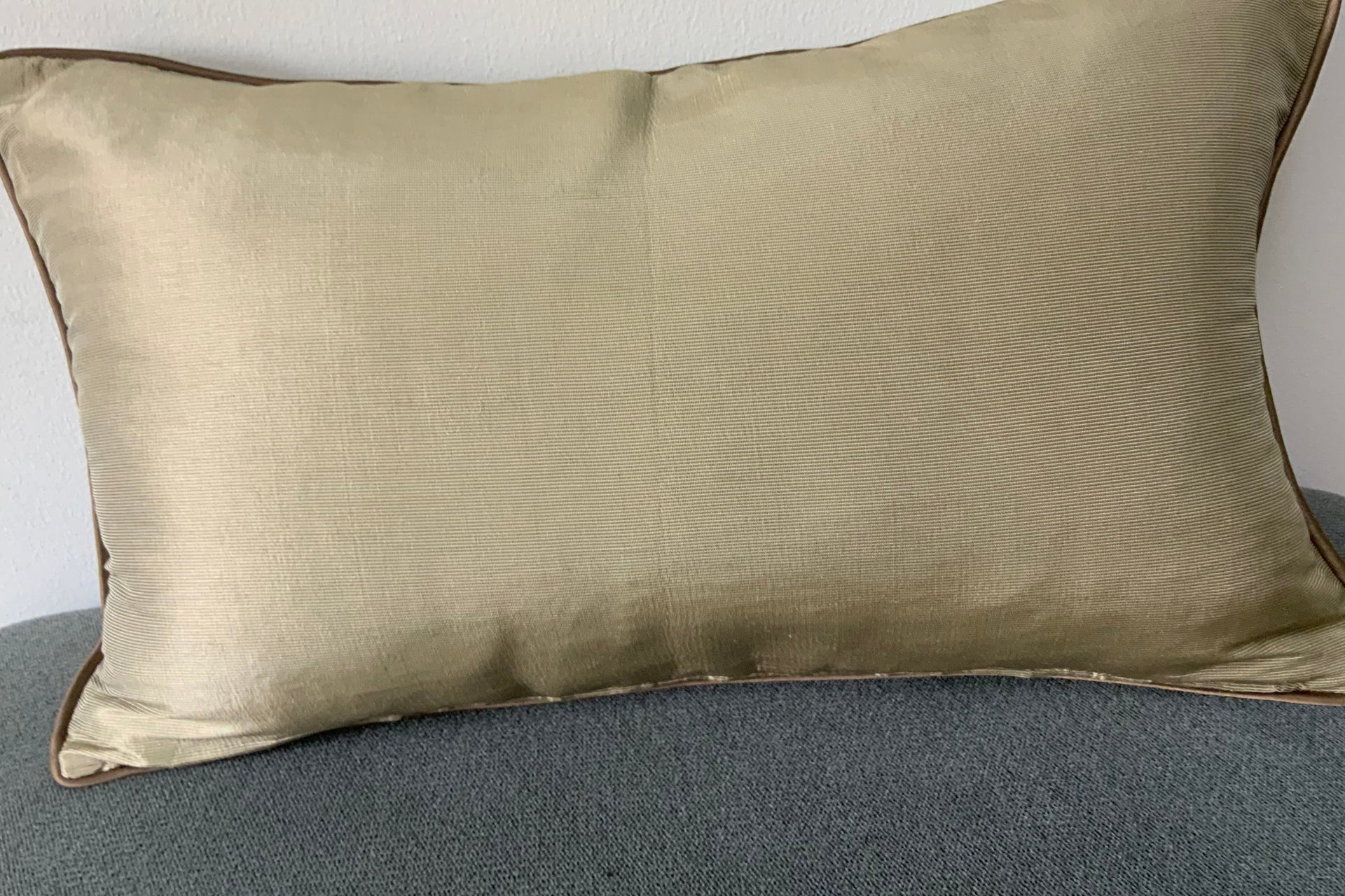 rectangular champagne gold silk-textured lumbar pillow  featuring dark bronze contrast piping,