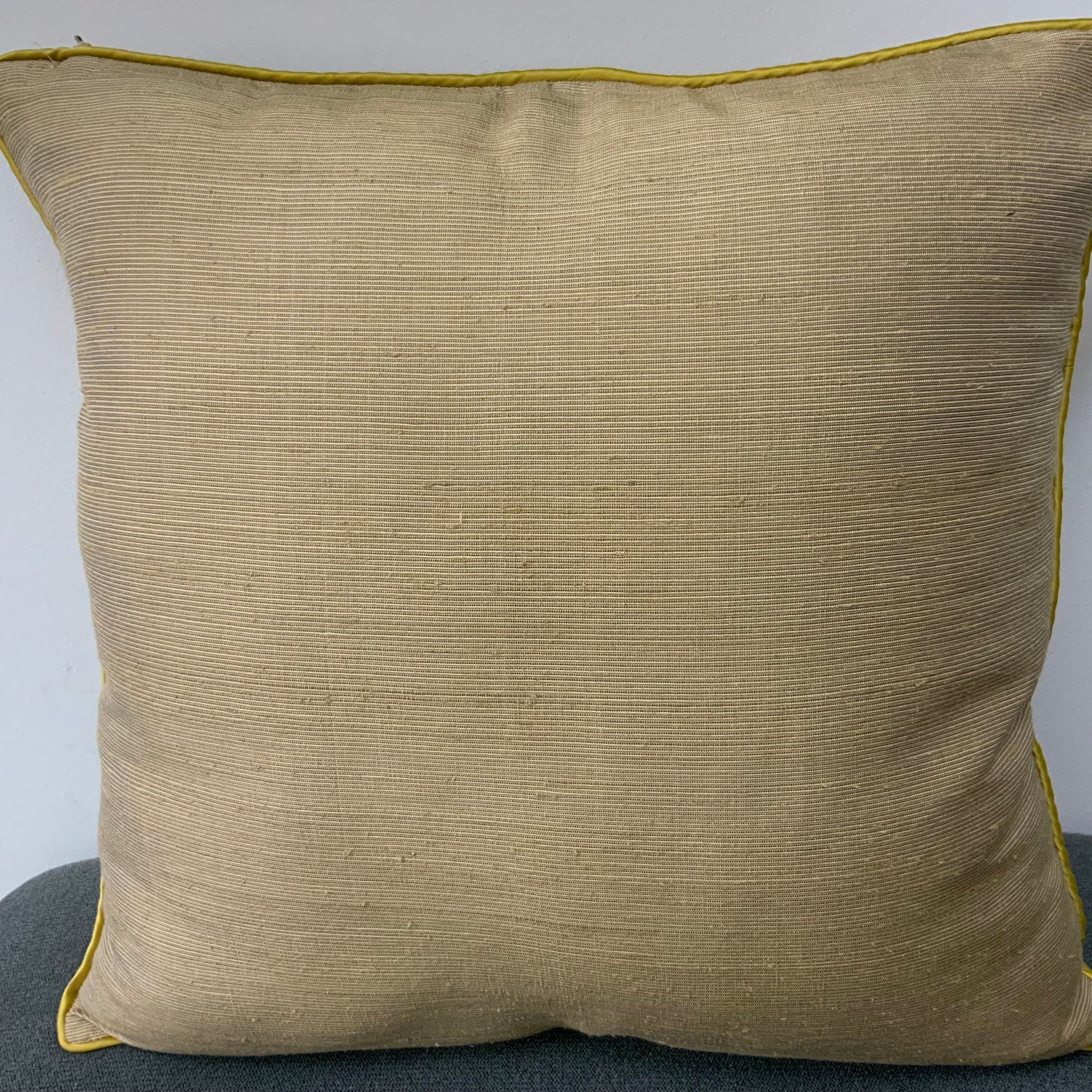 Square sand-colored textured fabric throw pillow cover with vibrant yellow-green piping.