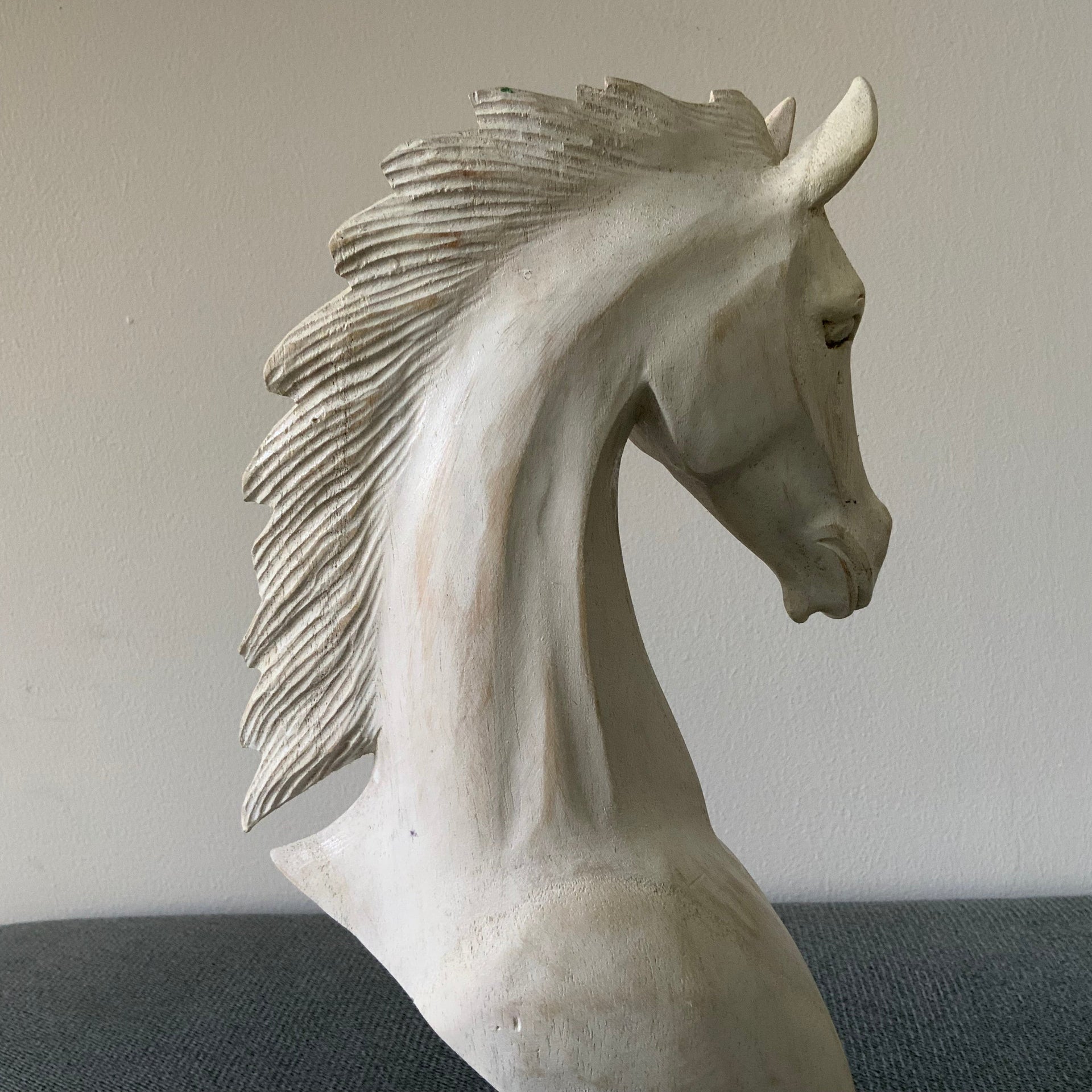 White horse sculpture on a gray surface with a neutral background